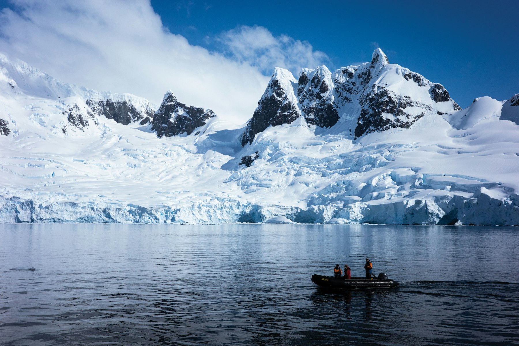 Guests in a Zodiac below a glacier on the Antarctic Peninsula