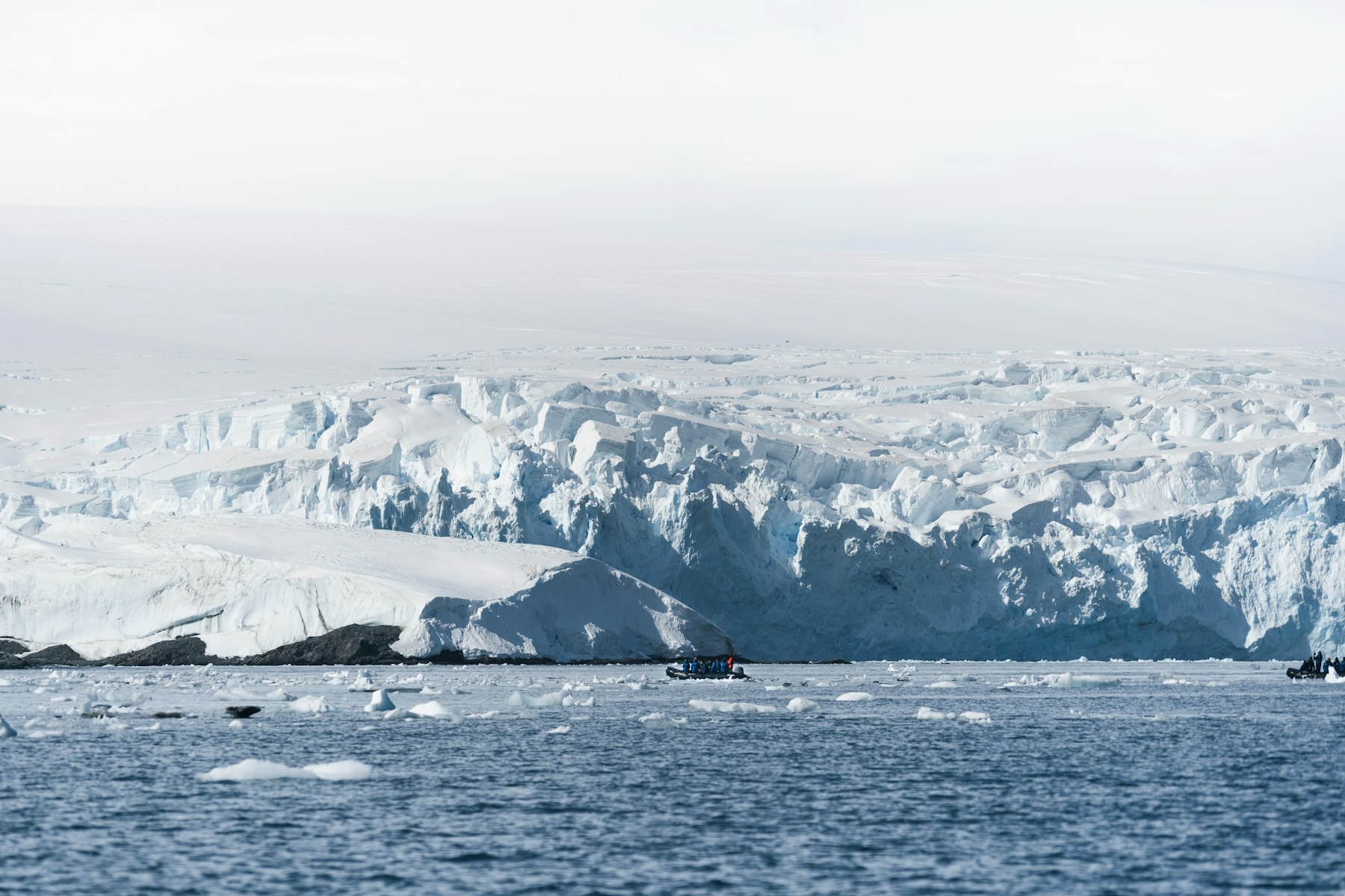 A Zodiac crossing open water below an Antarctic glacier